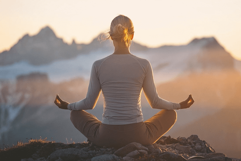 A serene and introspective individual sitting cross-legged on a mountain summit during sunrise, symbolizing resilience and inner strength.