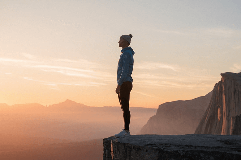 individual standing at the edge of a cliff during sunrise, symbolizing resilience and mental strength.