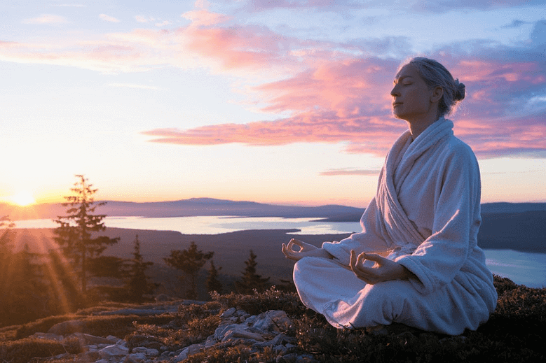 A serene sunrise with a person meditating on a mountaintop for Mindfulness Day Celebration.